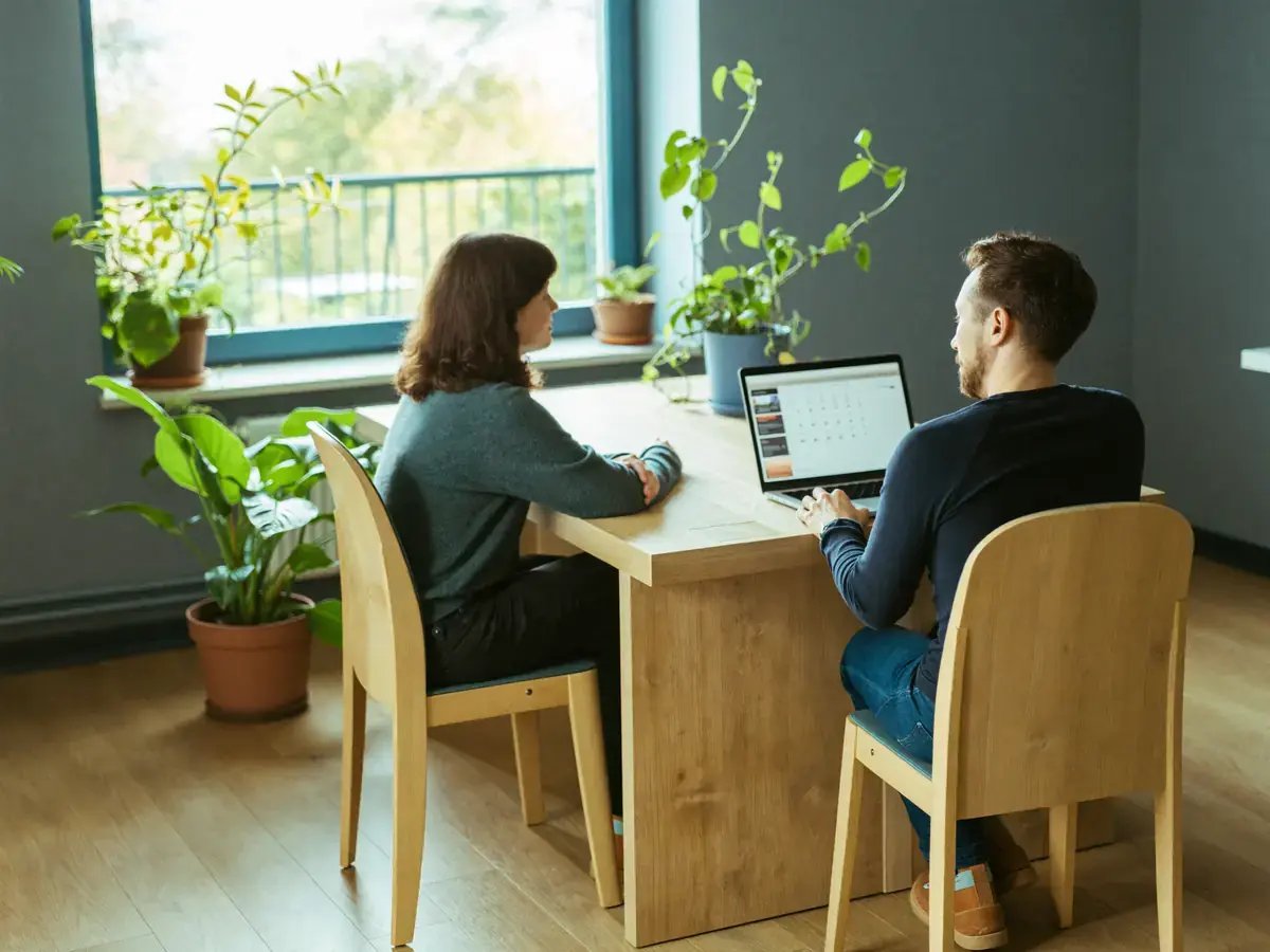 Zwei Kolleginnen und Kollegen einer Ferienhausagentur am Schreibtisch mit Laptop
